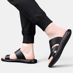Black sandals worn with black pants on a light gray background