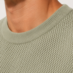 Close-up of a man wearing a textured sage green crewneck sweater, showing the ribbed collar and fine knit pattern.