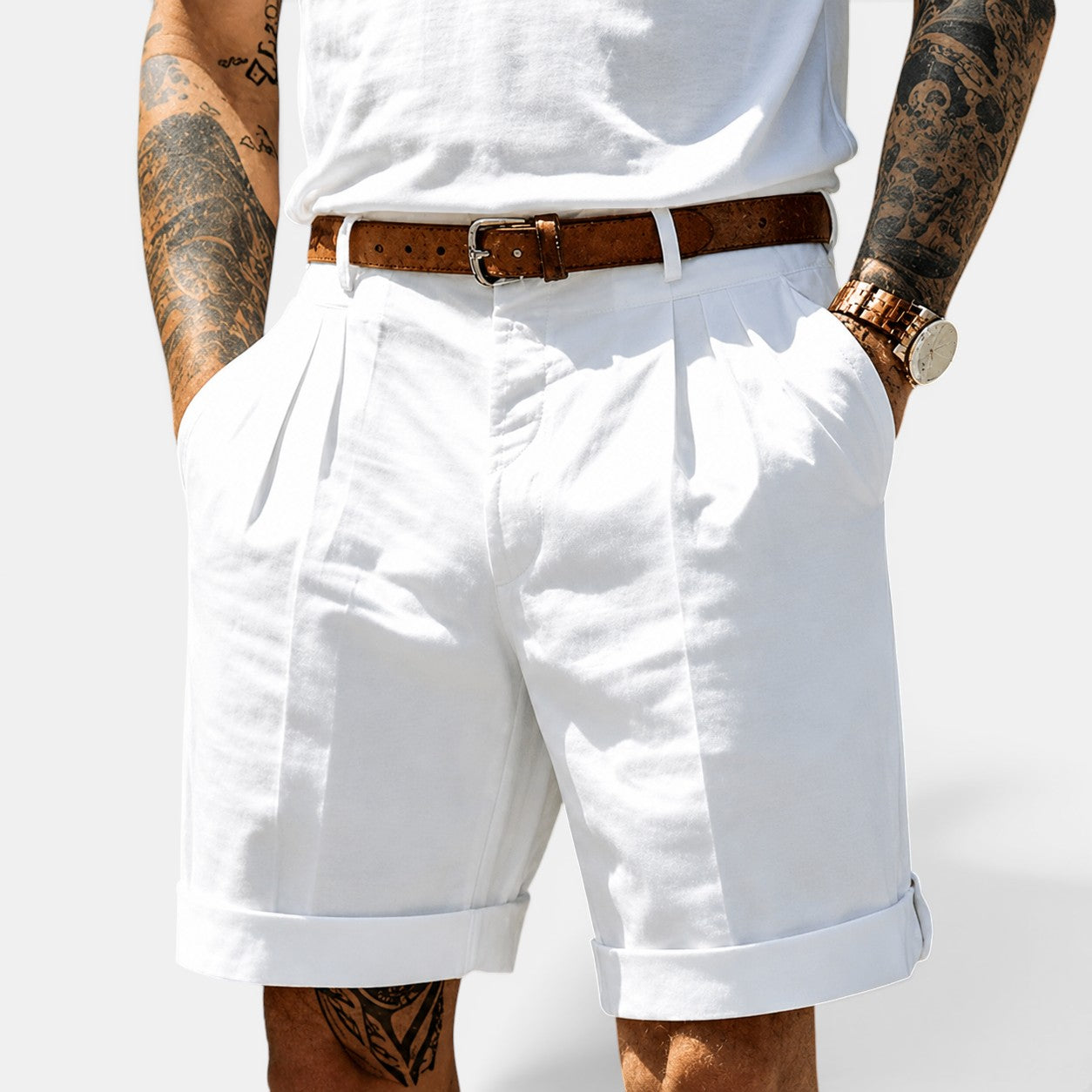 Person wearing white shorts and a white tank top with a brown belt on a light gray background