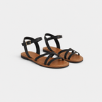 Black strappy sandals with brown soles on a light gray background