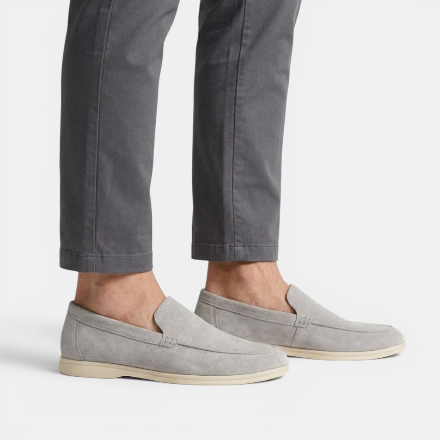 Gray loafers worn with gray pants on a white background