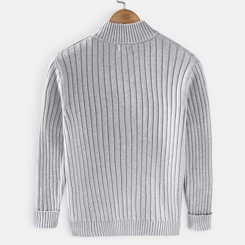 Gray ribbed sweater on a wooden hanger against a white background