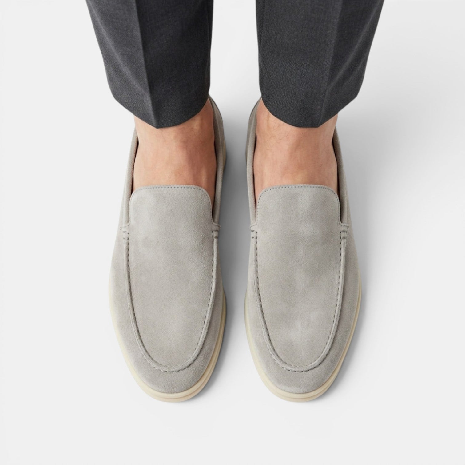 Gray loafers worn with dark pants on a white background