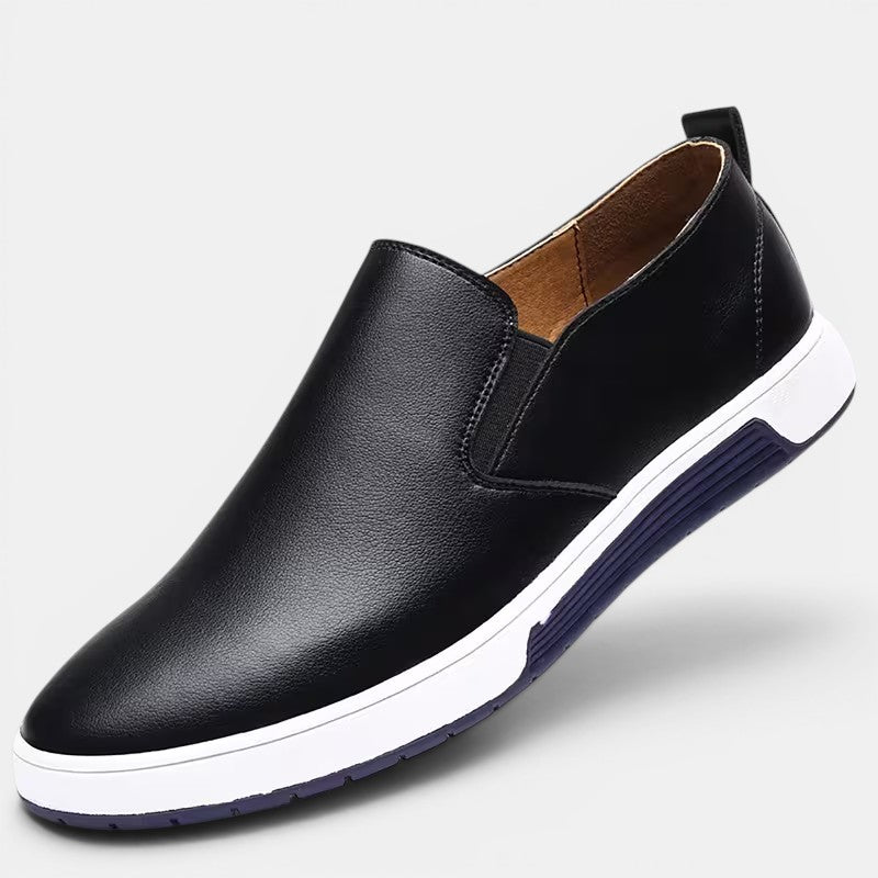 Black leather slip-on shoe with white sole on a light gray background