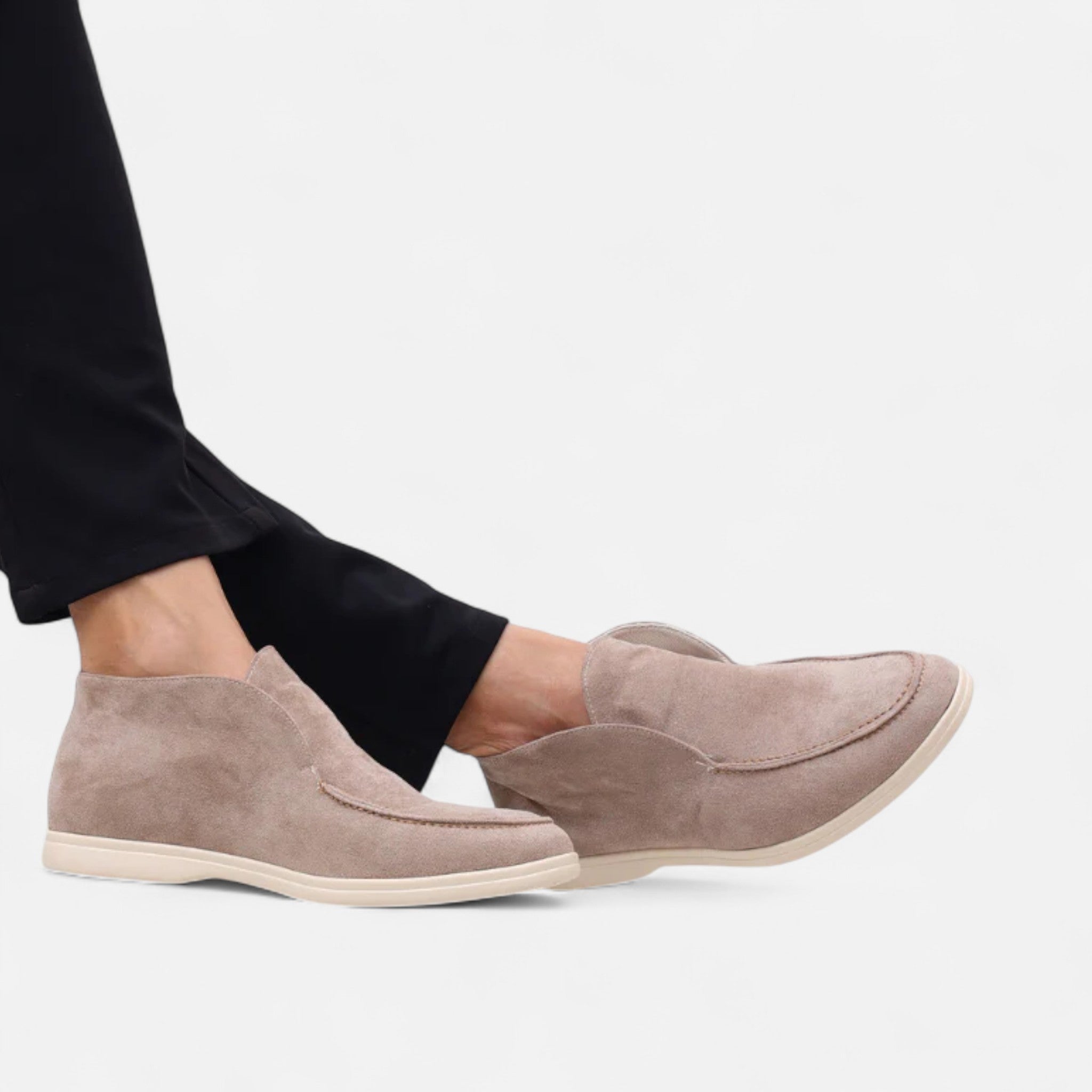 Beige loafers worn with black pants on a white background