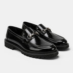 Black loafers with chain details on a white background