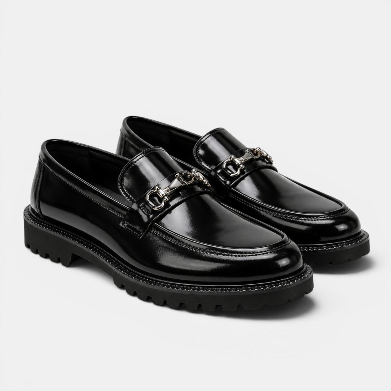 Black loafers with chain details on a white background