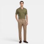 Man wearing a green polo shirt and beige pants on a white background