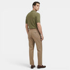 Man wearing a green polo shirt and beige pants on a white background