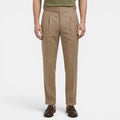 Beige pleated pants worn by a person on a white background