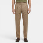 Beige pleated pants worn by a person on a white background
