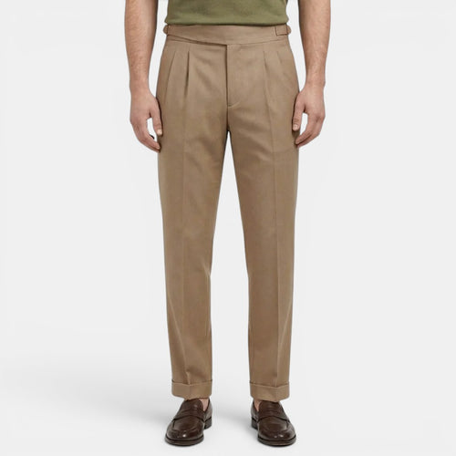 Beige pleated pants worn by a person on a white background