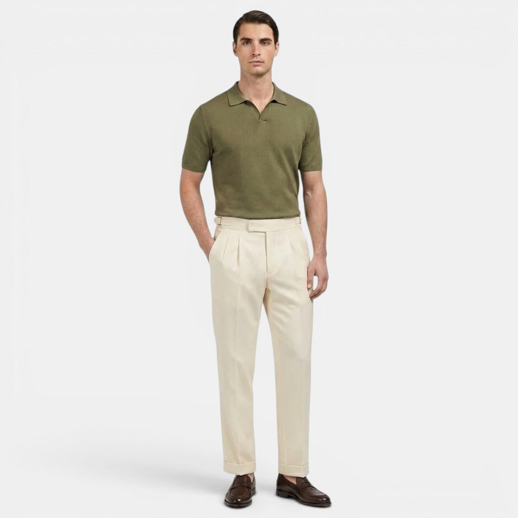 Man wearing a green polo shirt and beige pants on a white background