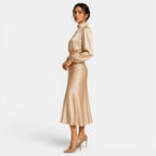 Woman wearing a gold satin dress on a white background