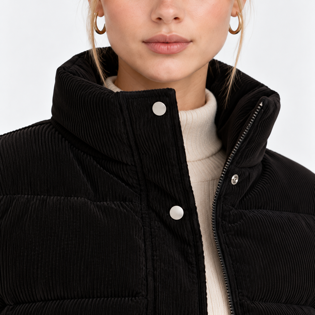 Close-up of women's black puffer jacket with high collar, snap button closure, and quilted texture