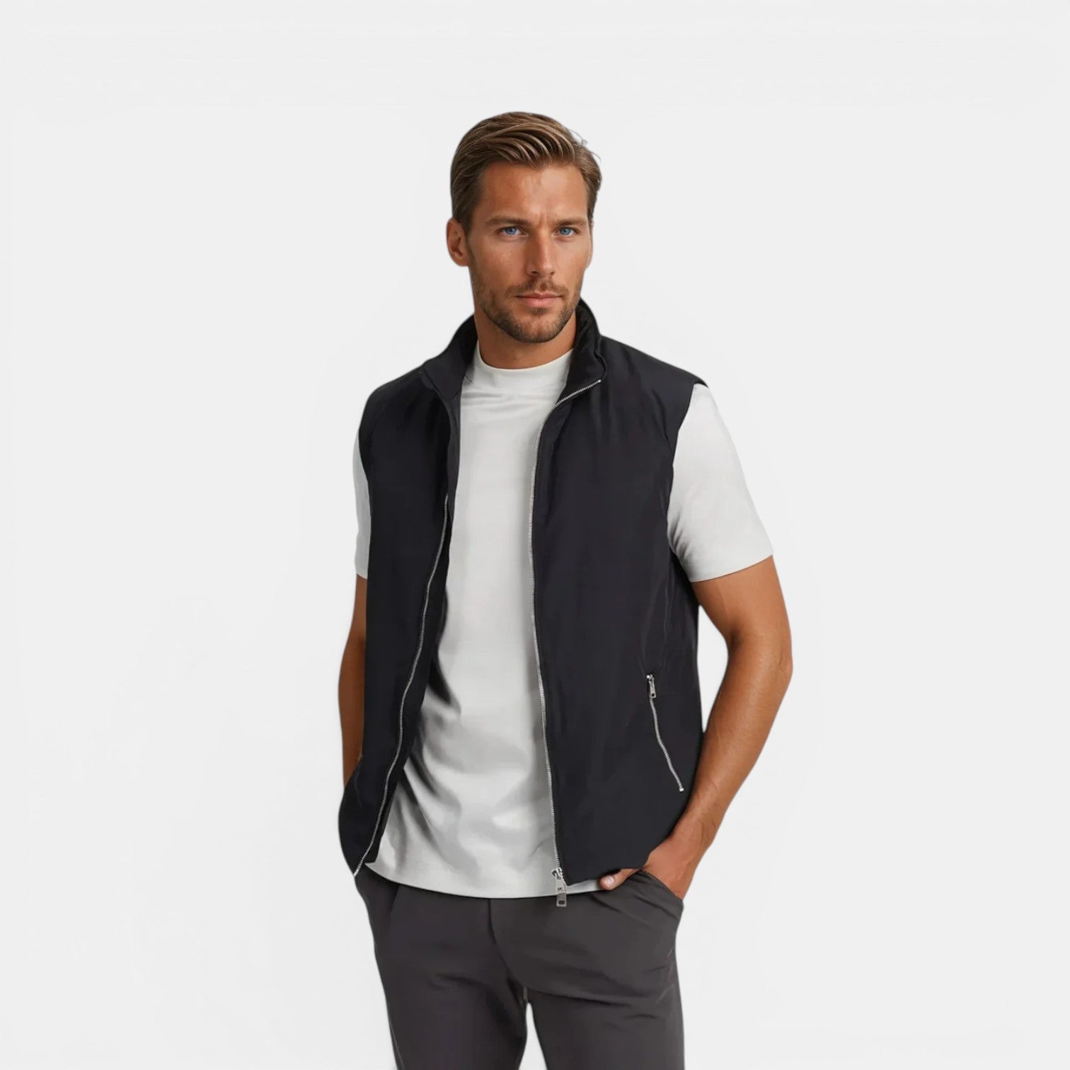 Man wearing a black vest over a white shirt on a light gray background