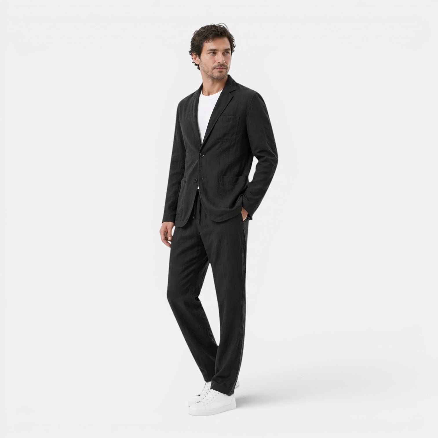 Man wearing a black suit and white sneakers on a white background