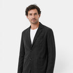 Man wearing a black jacket over a white shirt on a white background