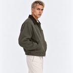 Side view of a man wearing an olive green jacket with brown corduroy collar