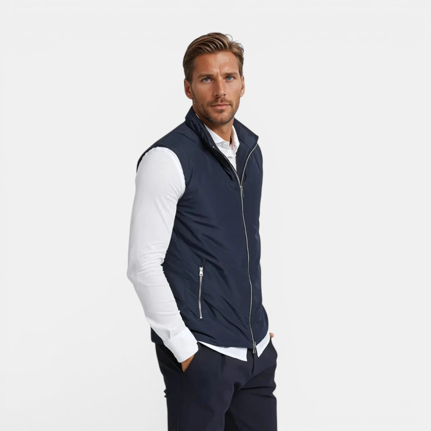Man wearing a navy vest over a white shirt on a light gray background