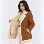 Side view of a woman wearing a brown shearling coat with cream faux fur lining