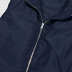 Close-up of a navy blue jacket with a zipper on a light gray background