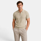Man wearing a beige ribbed knit polo shirt with matching tailored trousers against a light gray background.