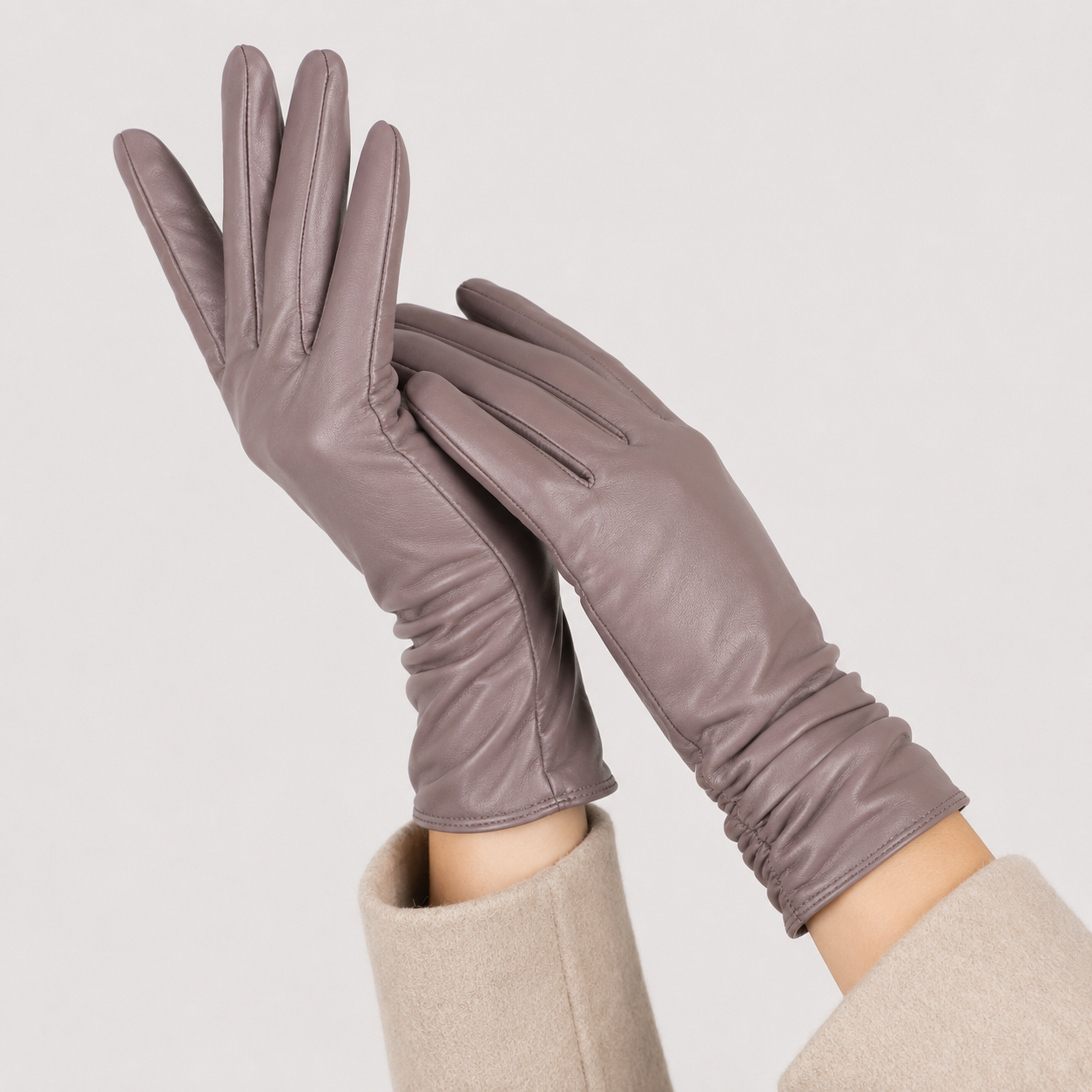 A pair of long, slim gloves in a muted taupe-brown color, worn on hands with beige sleeves visible against a plain light gray background.