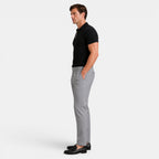 Side view of a man wearing a black ribbed knit polo shirt with gray trousers and black loafers.