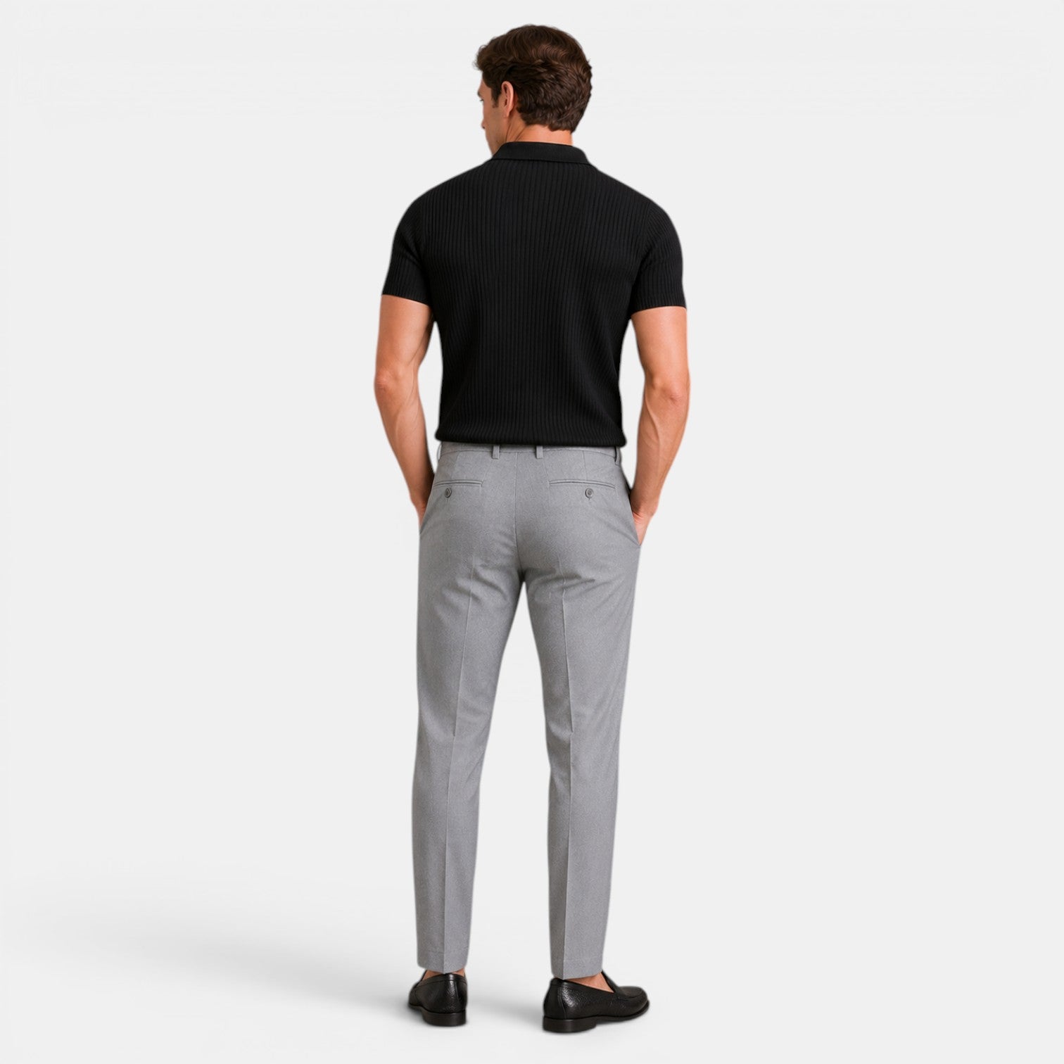 Back view of a man wearing a black ribbed knit polo shirt with gray trousers and black loafers.