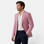 Side view of a young man wearing a pink checked blazer, white dress shirt, and navy trousers.