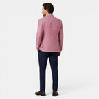 Back view of a young man wearing a pink checked blazer, navy trousers, and brown loafers.