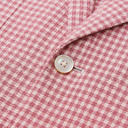 Close-up of a pink houndstooth blazer featuring textured fabric and a classic button detail.