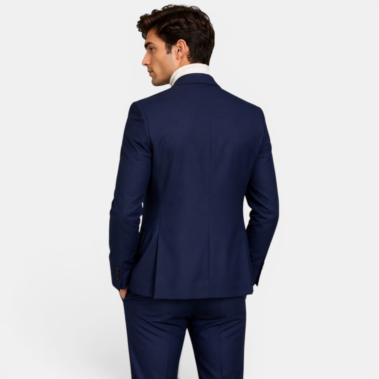 Back view of a young man wearing a navy blue suit and cream turtleneck sweater.