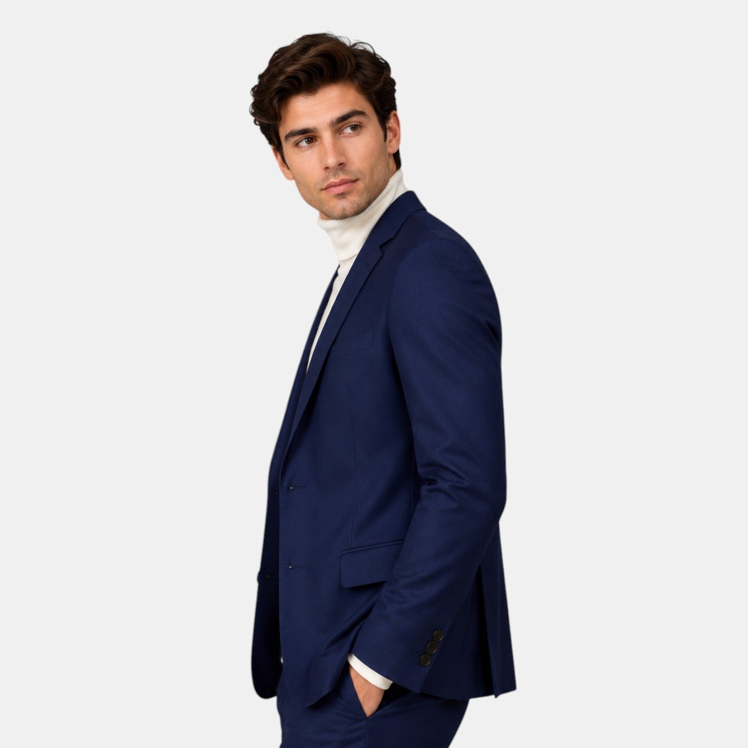 Side view of a young man wearing a navy blue suit and cream turtleneck sweater.