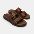 Pair of brown sandals with buckles on a light gray background