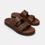 Pair of brown sandals with buckles on a light gray background