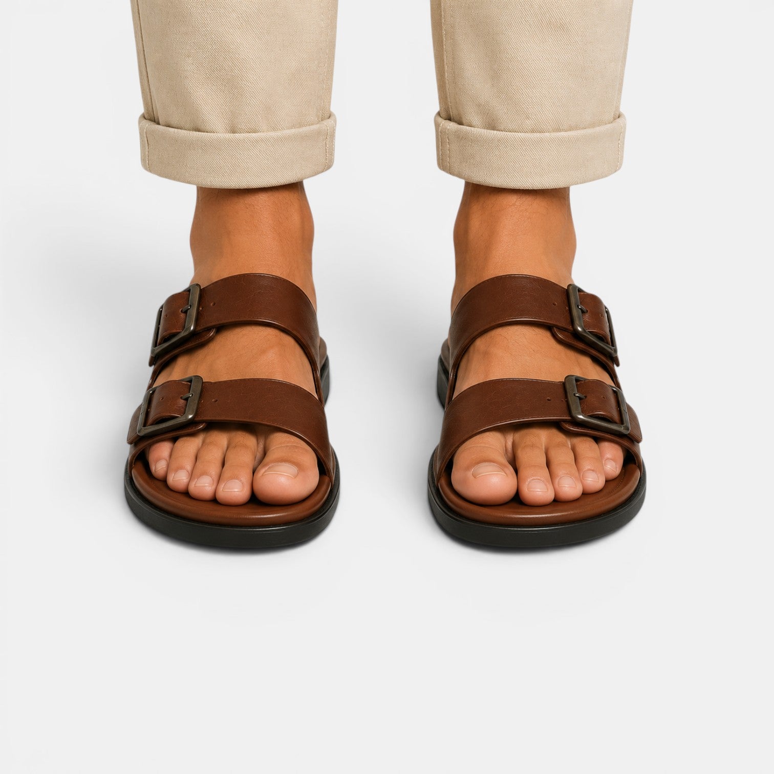 Brown sandals worn with beige pants on a light gray background