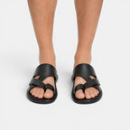 Black sandals worn by a person on a white background