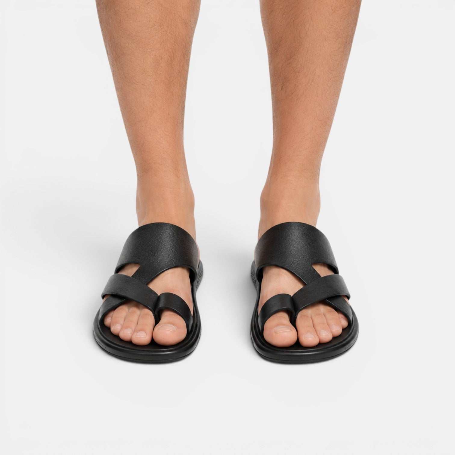 Black sandals worn by a person on a white background