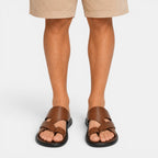 Brown sandals worn with beige shorts on a white background