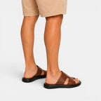 Brown sandals worn with beige shorts on a white background