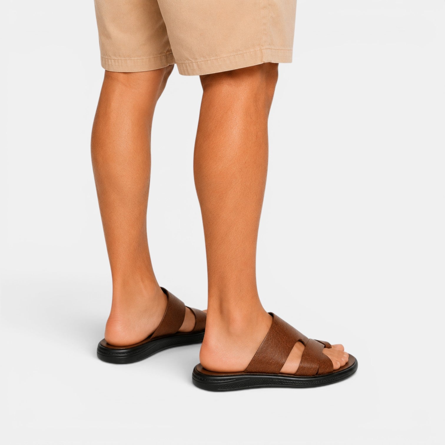 Brown sandals worn with beige shorts on a white background