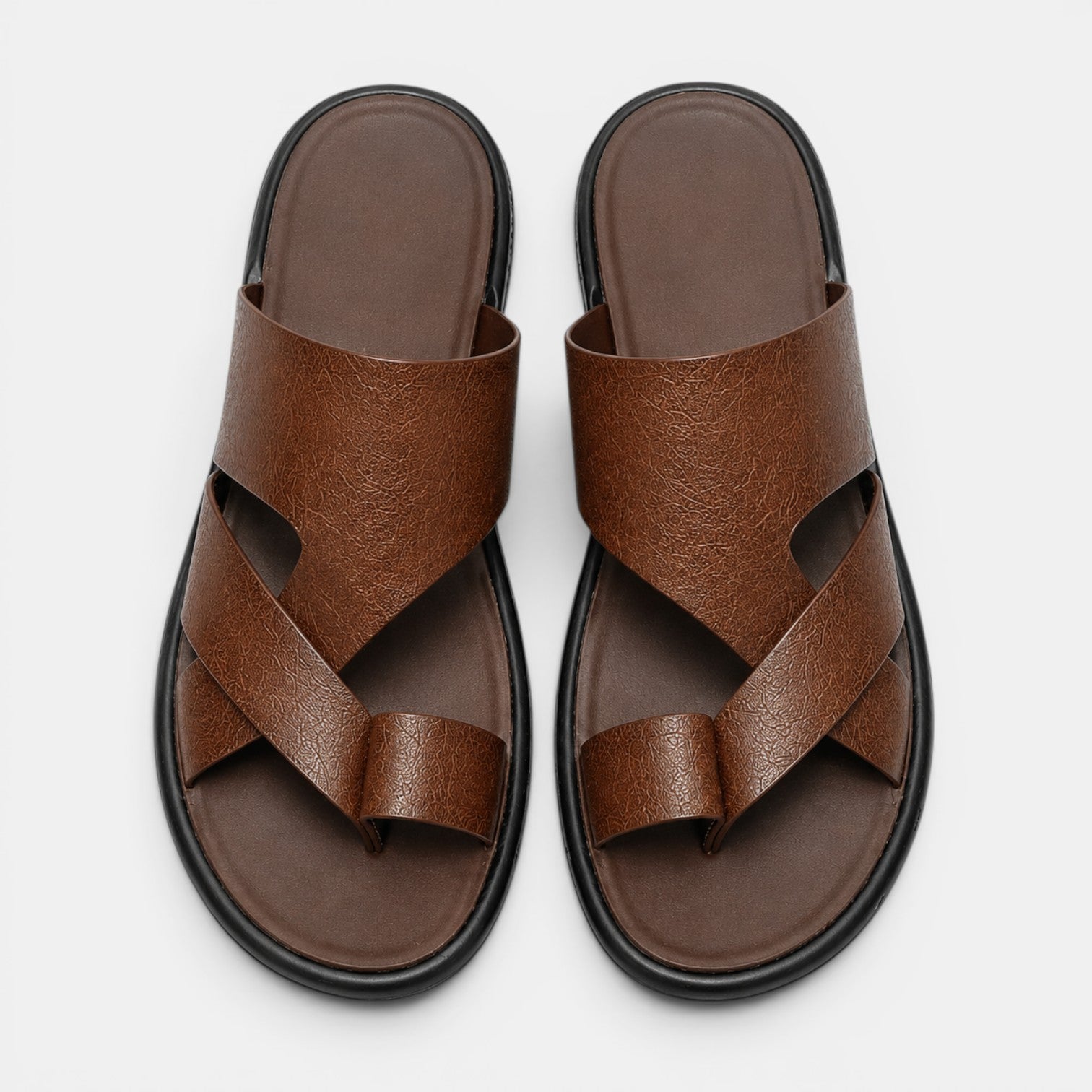 Pair of brown sandals with criss-cross straps on a white background