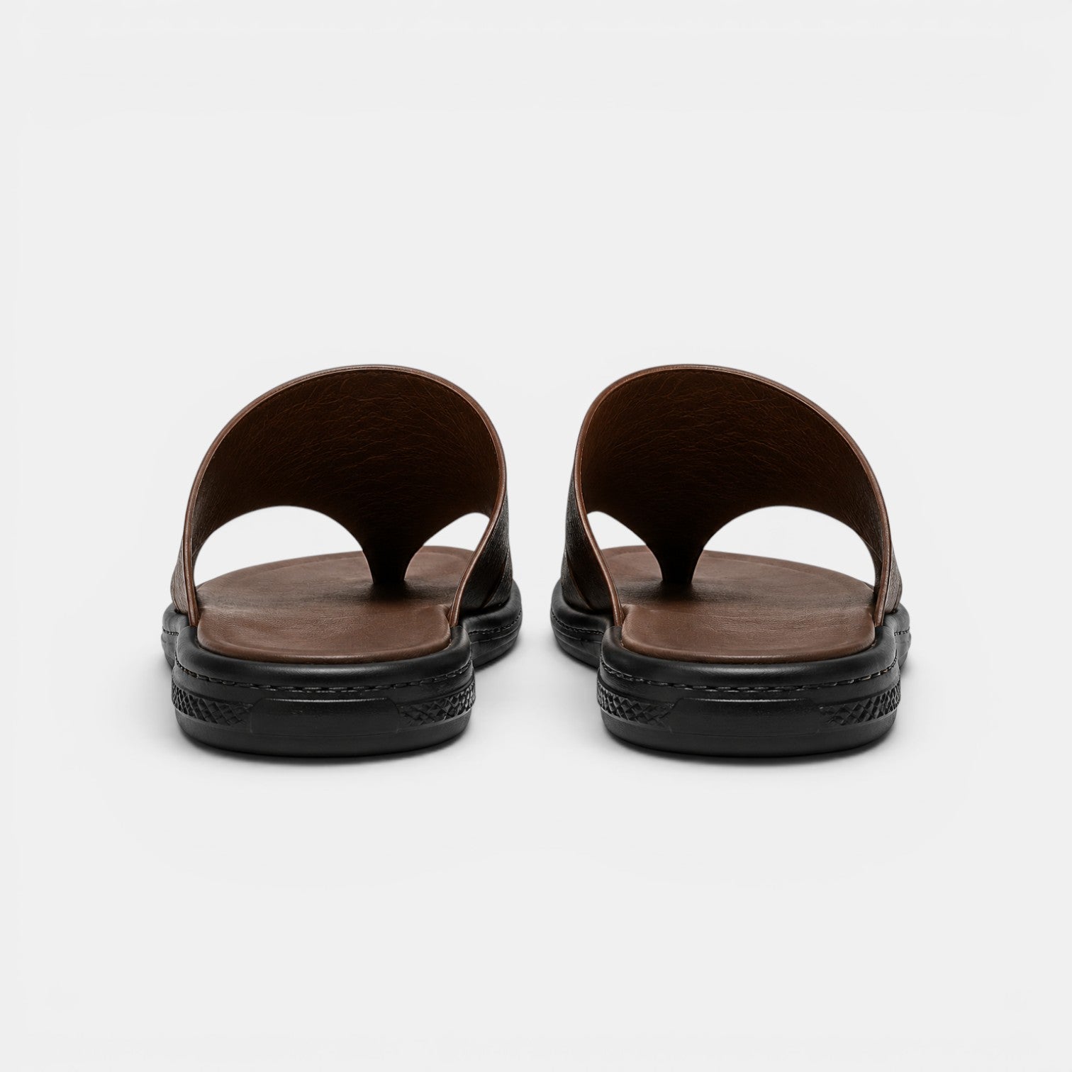 Pair of brown sandals with black soles on a white background