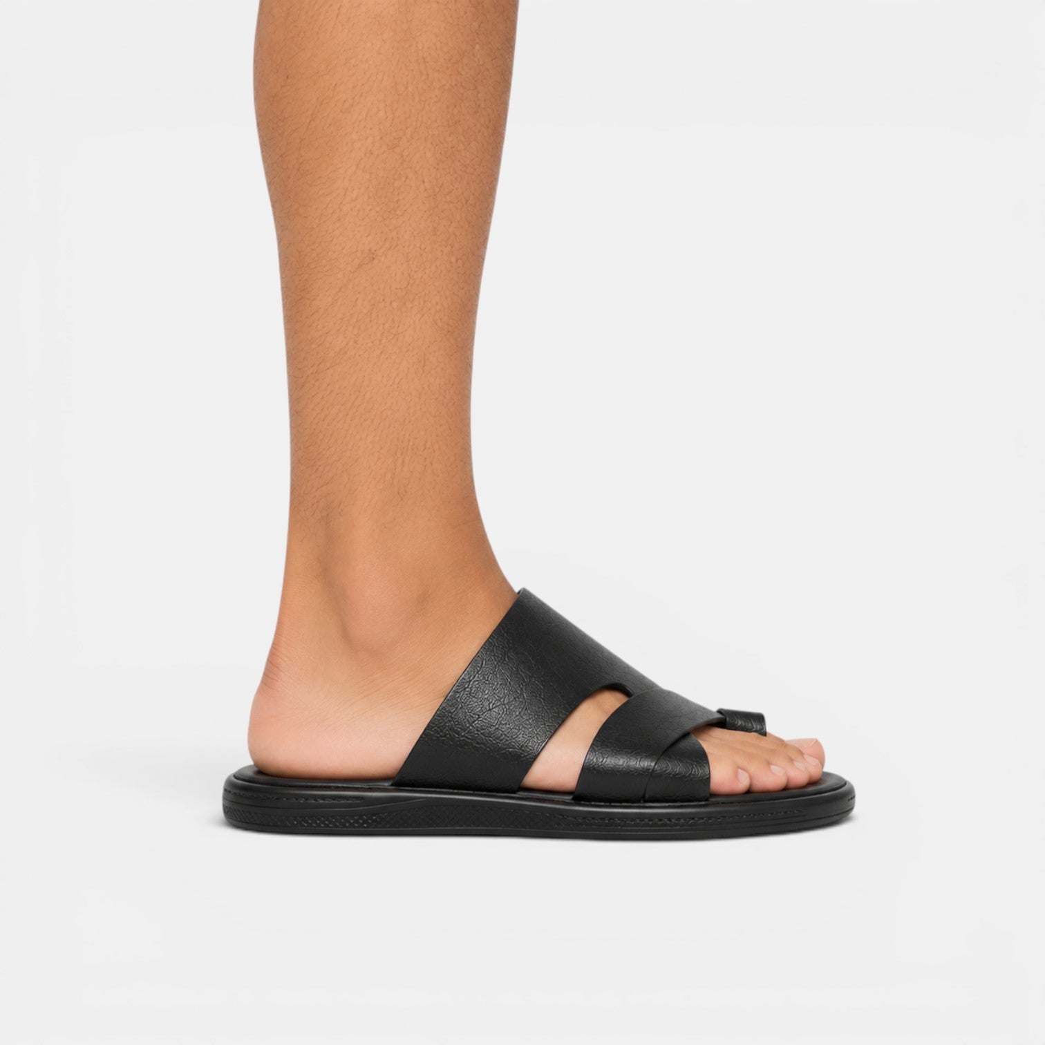 Black sandal worn on a foot against a white background