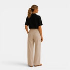 Woman wearing a black top and beige pants on a white background