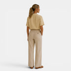 Woman wearing a beige shirt and pants on a white background