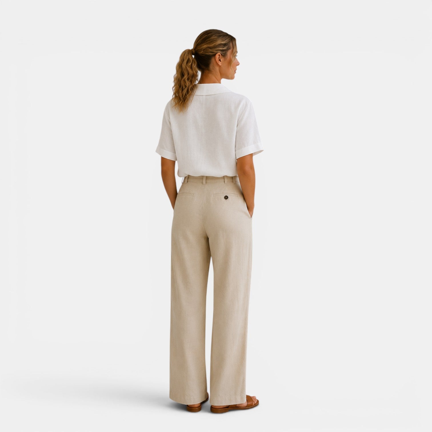 Woman wearing a white shirt and beige pants on a white background