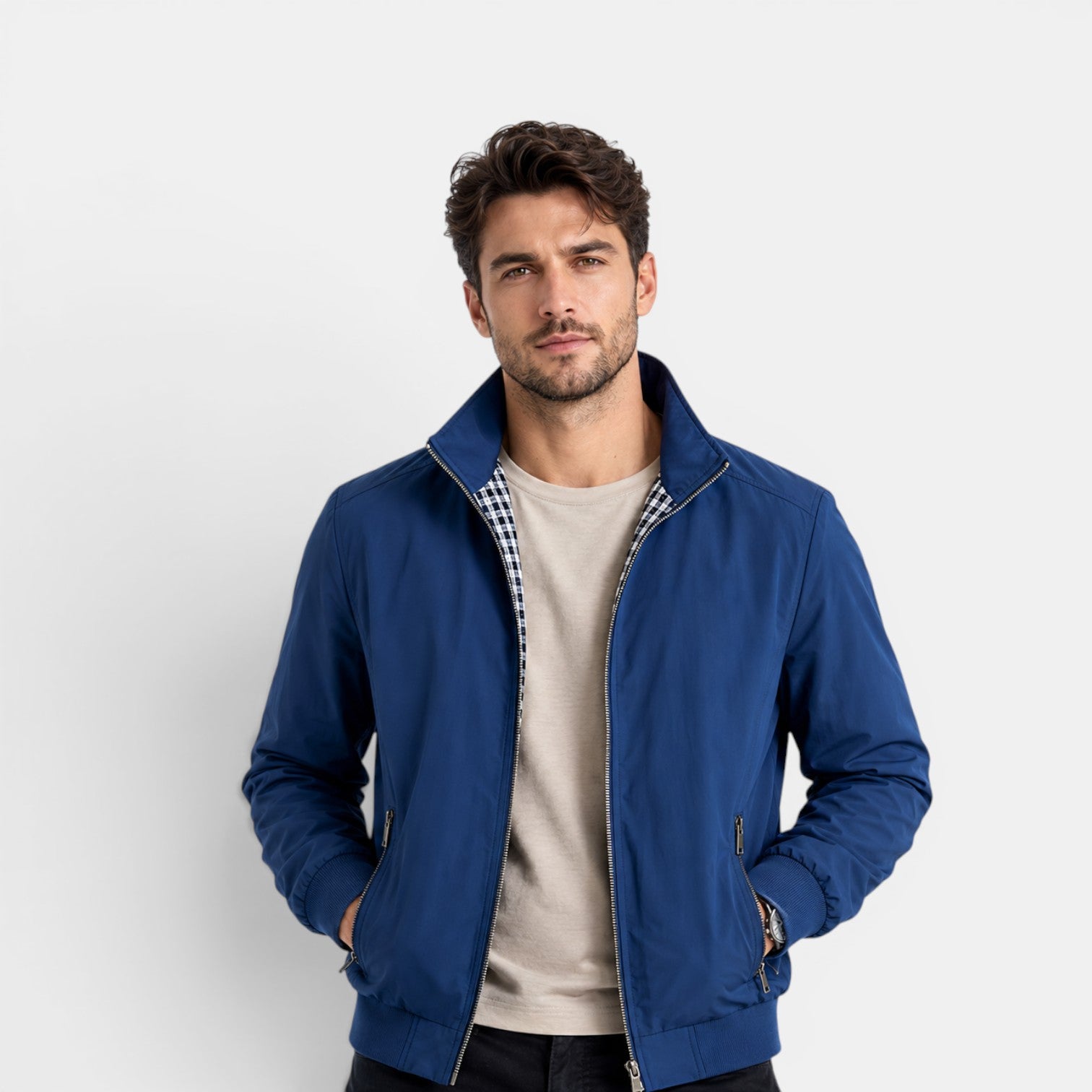 Man wearing a blue jacket over a checkered shirt on a white background